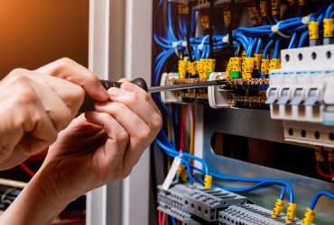 The man is repairing the switchboard voltage with automatic switches. Electrical background